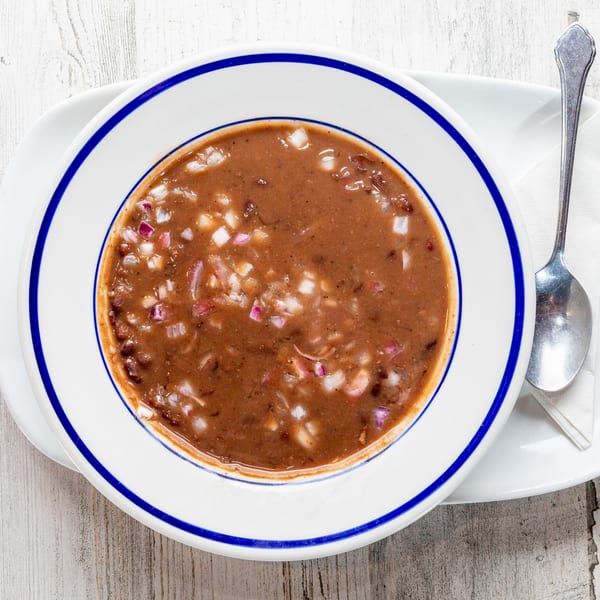 A bowl of White Wolf Cafe's black bean soup, topped with diced red and white onions.