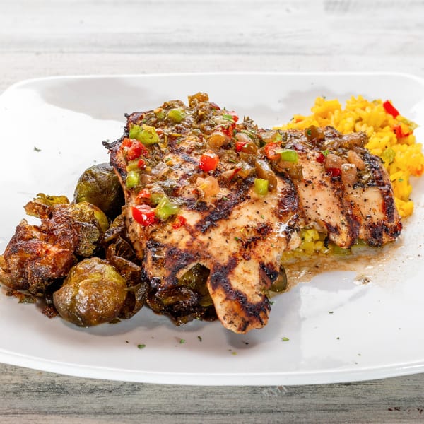 Grilled chicken with colorful salsa, roasted Brussels sprouts, and yellow rice on a white plate.
